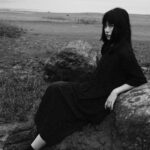 A woman sitting on a rock with a bridge in the background