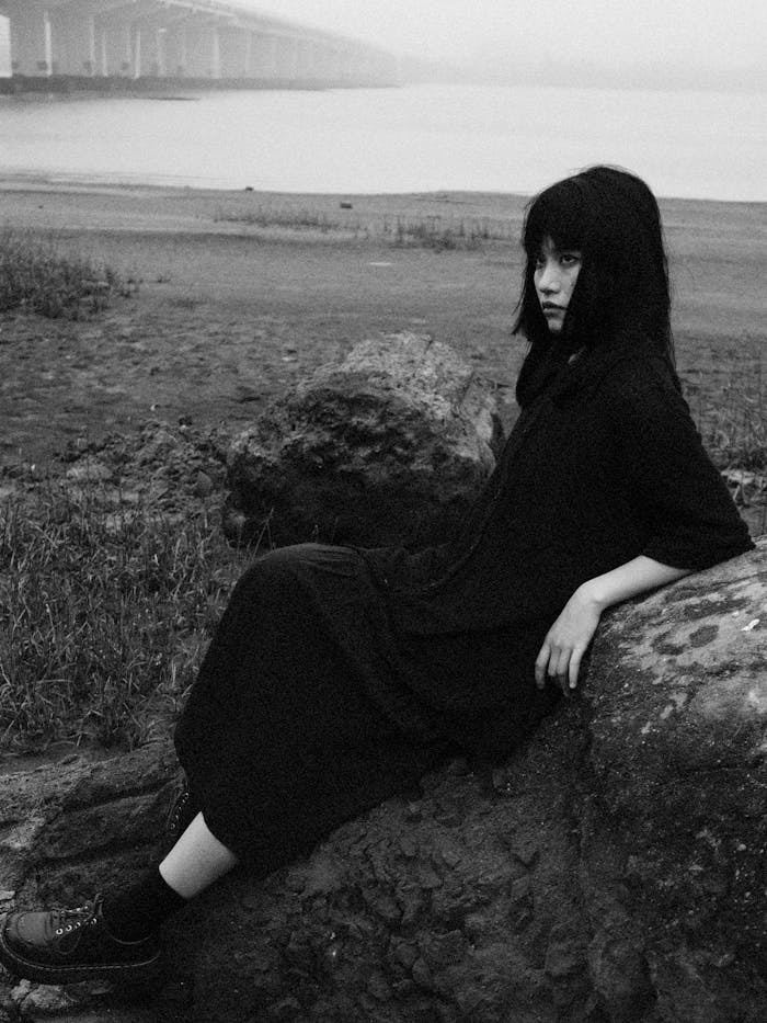 A woman sitting on a rock with a bridge in the background